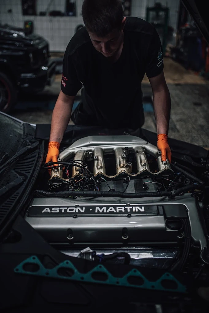 Klasyczny Mercedes z otwartą maską podczas naprawy w warsztacie specjalizującym się w autach premium.